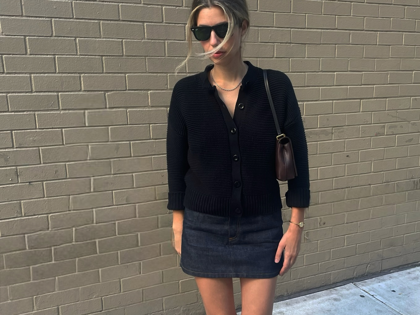 Robin Reetz in New York City wearing a black cardigan with a mini skirt, Jil Sander bag, and square-toe heels.