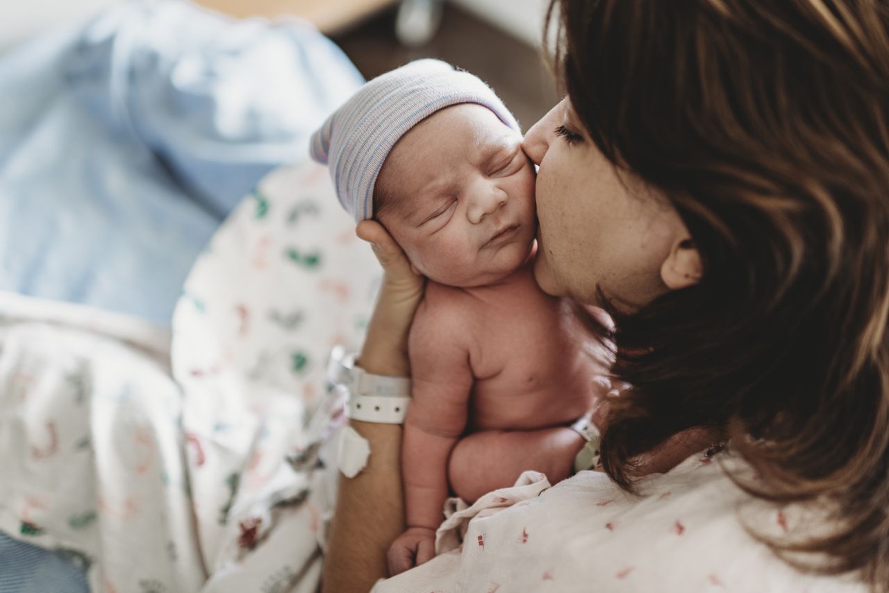 Close up detail of mother kissing newborn son&#039;s cheek in hospital