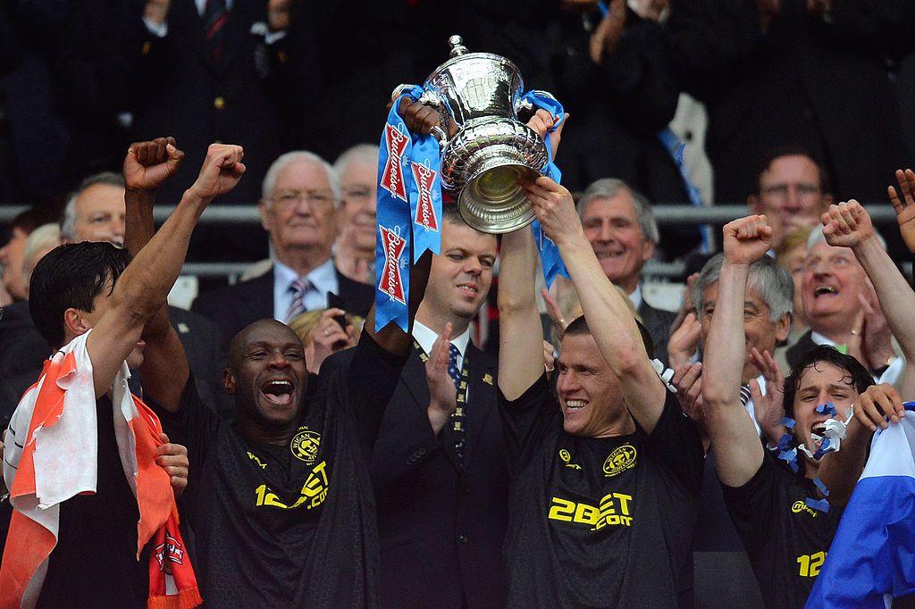 Wigan Athletic&#039;s Barbadian defender Emmerson Boyce (L) and Wigan Athletic&#039;s Scottish defender Gary Caldwell (R) raise the FA Cup after winning the English FA Cup final football match between Manchester City and Wigan Athletic at Wembley Stadium in London on May 11, 2013. Substitute Ben Watson scored an injury-time winner to give Wigan Athletic a sensational 1-0 win over Manchester City at Wembley Stadium on Saturday in the biggest FA Cup final upset in 25 years. AFP PHOTO / ANDREW YATES NOT FOR MARKETING OR ADVERTISING USE / RESTRICTED TO EDITORIAL USE (Photo credit should read ANDREW YATES/AFP via Getty Images)