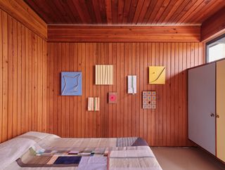 Bedroom with wood paneled wall and artworks on display