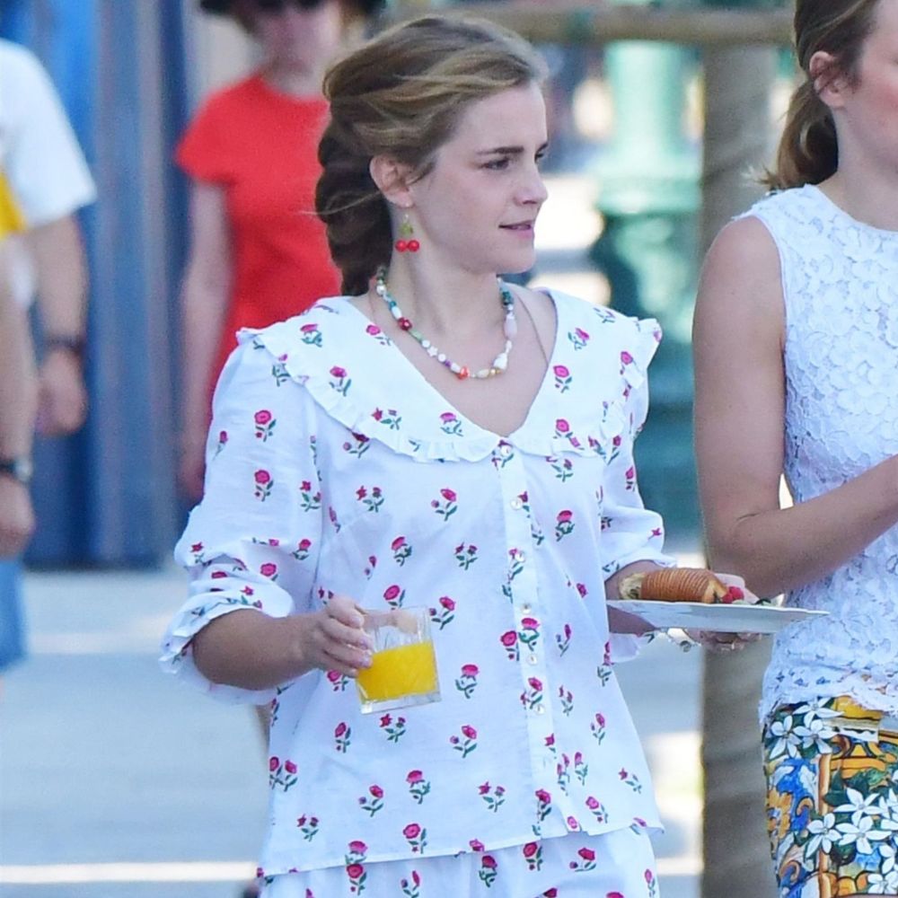 Emma Watson wears woven loafers with a matching floral cotton set. She's holding and orange juice and a plate with a croissant.