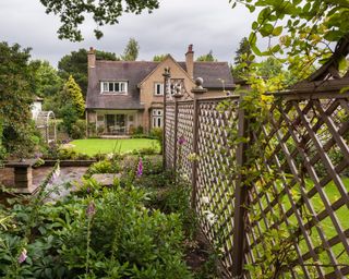 Small terraced area (stone sundial screened by trellis fence) lawn, arbour & house - beautiful, traditional, landscaped garden