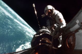 Dick Gordon seen during the first of his two Gemini 11 spacewalks working between his spacecraft and the Agena target.