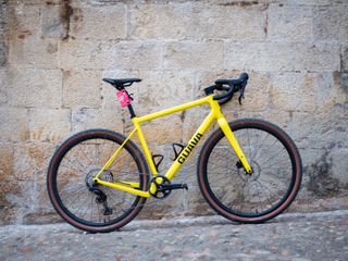 A yellow Guava Spot gravel bike leans against a wall