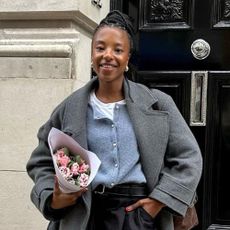 Influencer wears a blue cardigan with trousers and a grey coat.