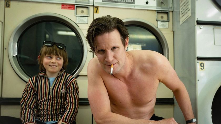 A shirtless Bunny Munro (Matt Smith) leans towards the camera with a half-smoked cigarette between his lips, observed admiringly by his son Bunny Junior (Rafael Mathé).
