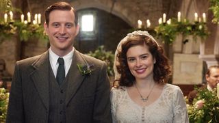 Nicholas Ralph as James in a tweed suit and tie and Rachel Shenton as Helen in a wedding dress in the church in All Creatures Great and Small.