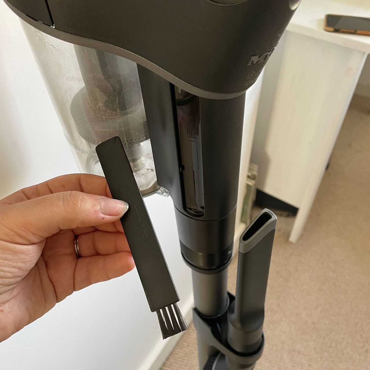 Miele DuoFlex vacuum, and a hand holding the onboard brush to clean the filter