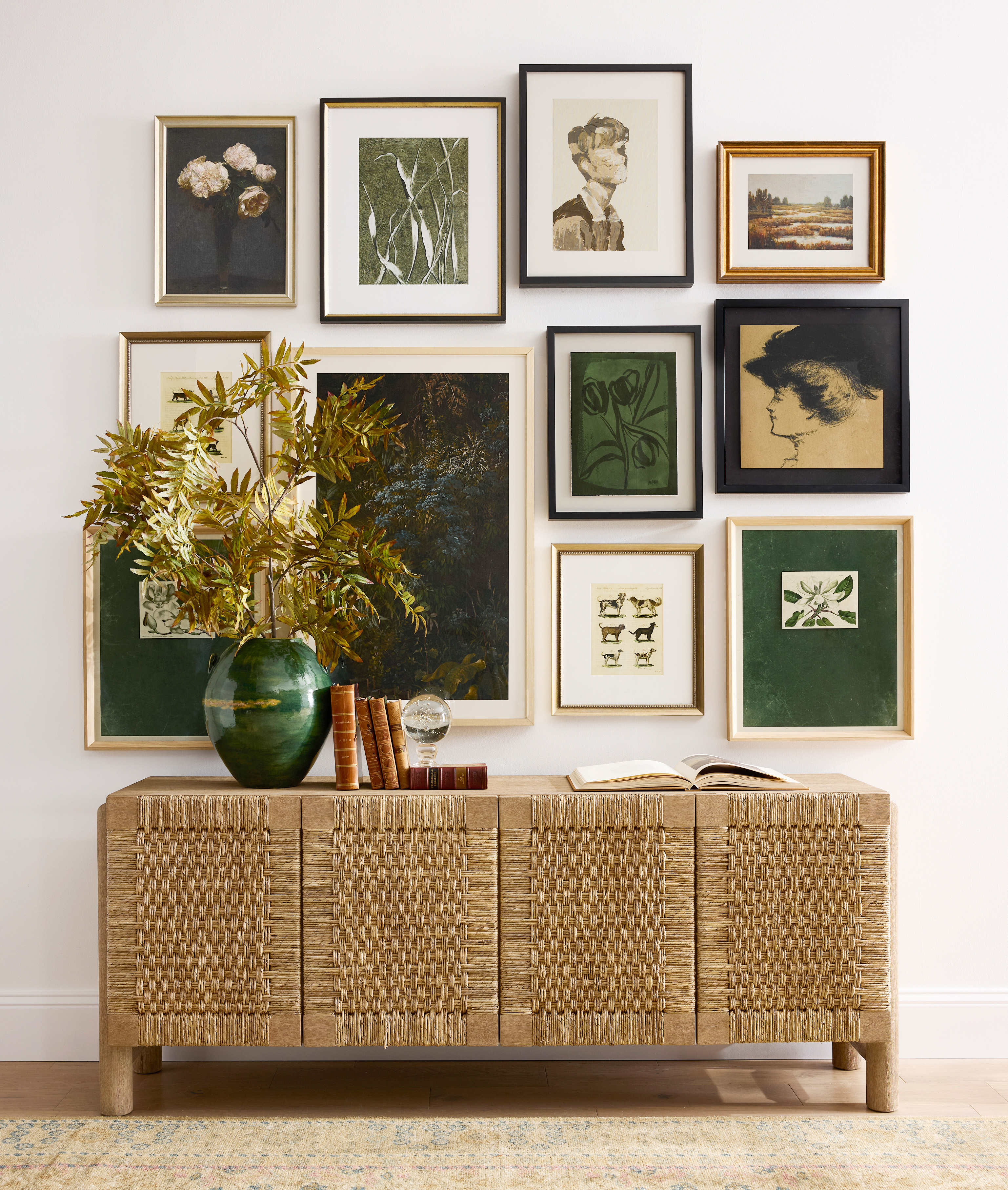 a woven credenza with a gallery wall above and green vase with foliage on top