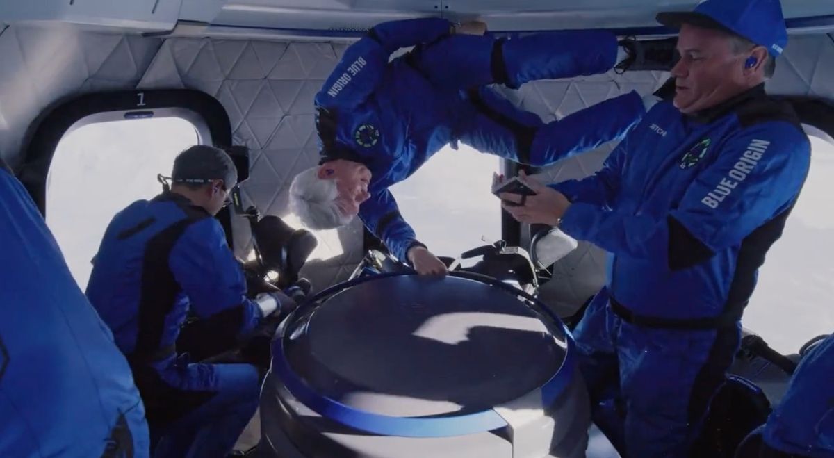 Businessman and professor Jim Kitchen, right, pulls out one of his passports during Blue Origin&#039;s NS-20 suborbital spaceflight on March 31, 2022. Kitchen brought 10 passports with him on the trip, as well as a Ukrainian flag and an American flag.