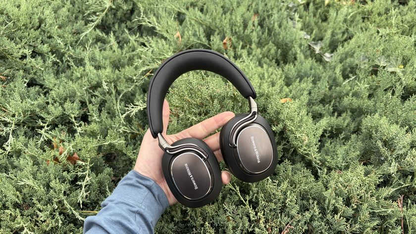Bowers &amp; Wilkins Px8 S2 headphones in black being held in front of a green bush