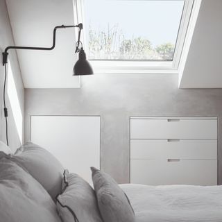 A minimalist bedroom with grey walls and a skylight
