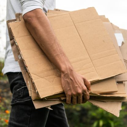 man carrying stack of cardboard outside