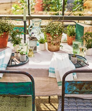garden entertaining table laid for lunch with green accessories and fresh foliage centrepiece