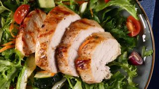 Sliced chicken on a bed of salad