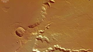 An aerial photo showing dents in the brown sandy surface of Mars