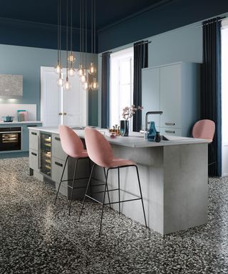 A modern kitchen with low level pendant lighting, kitchen island, pink bar stools, and Terazzo kitchen floor decor
