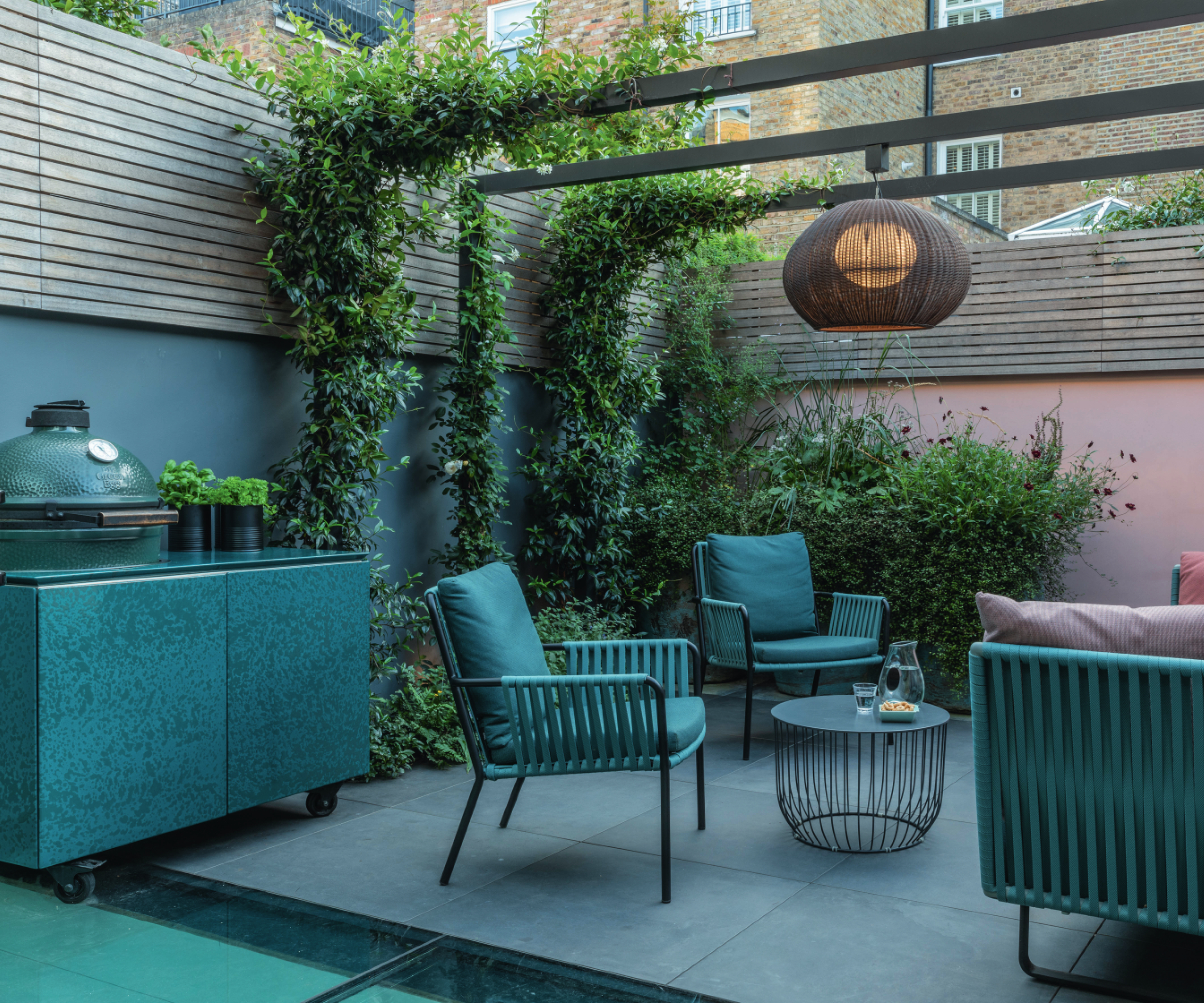 small patio with outdoor kitchen area, seating and wooden pergola