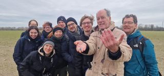 a group of people in warm jackets. one is holding a small rock