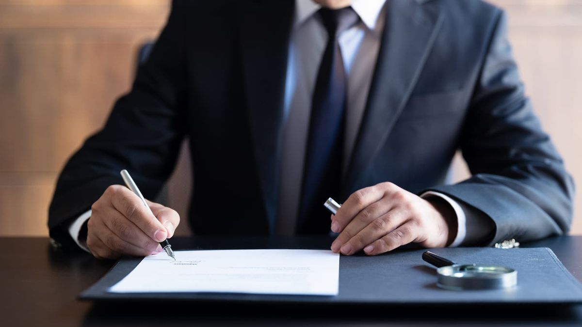 A man in a suit writing on paper