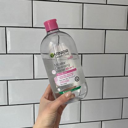 Garnier Micellar Water - lucy abbersteen holding a bottle of the micellar water up against white tiles