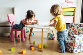 Young children playing on a small table at childminder or nursery