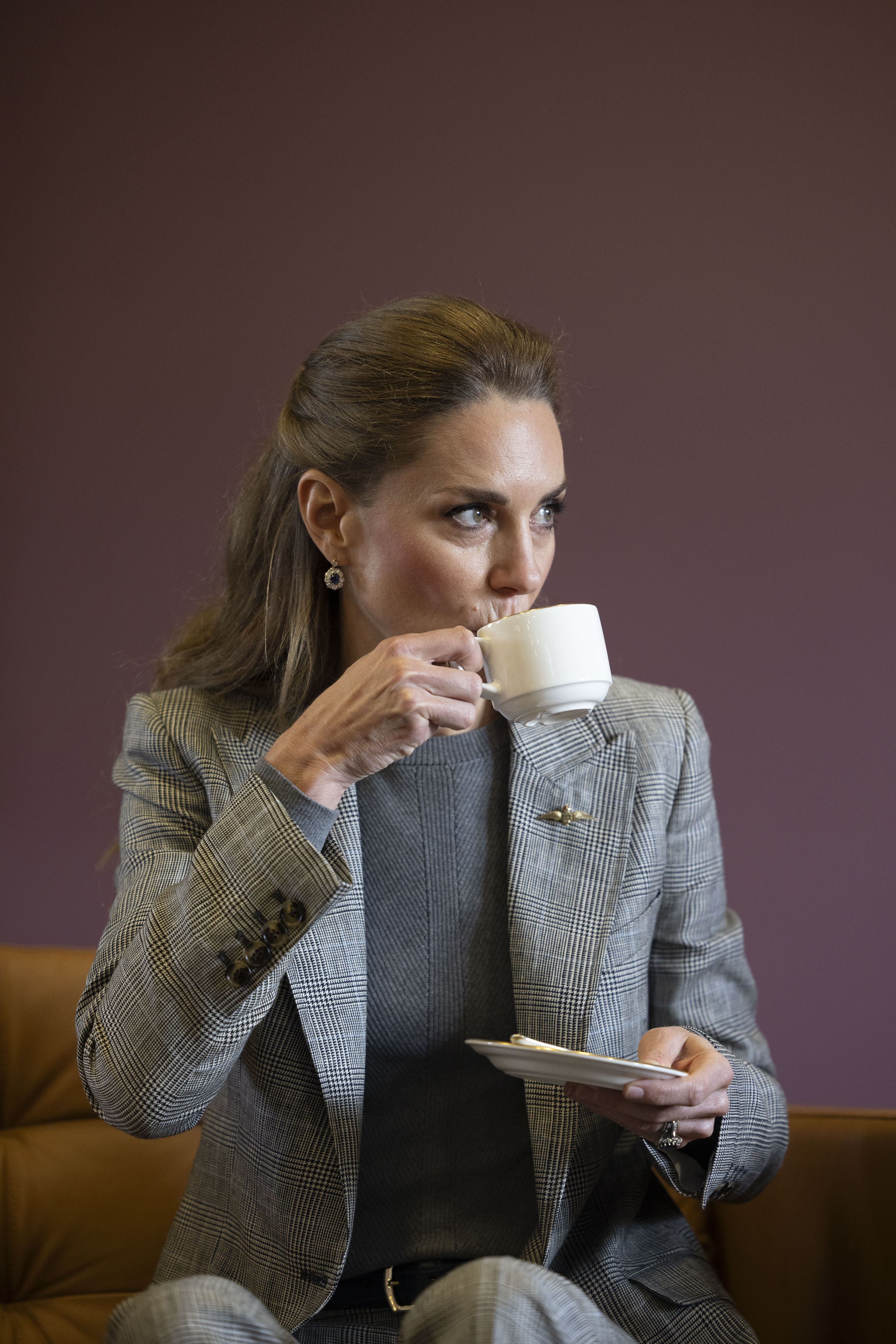 Kate Middleton drinking tea wearing a gray suit