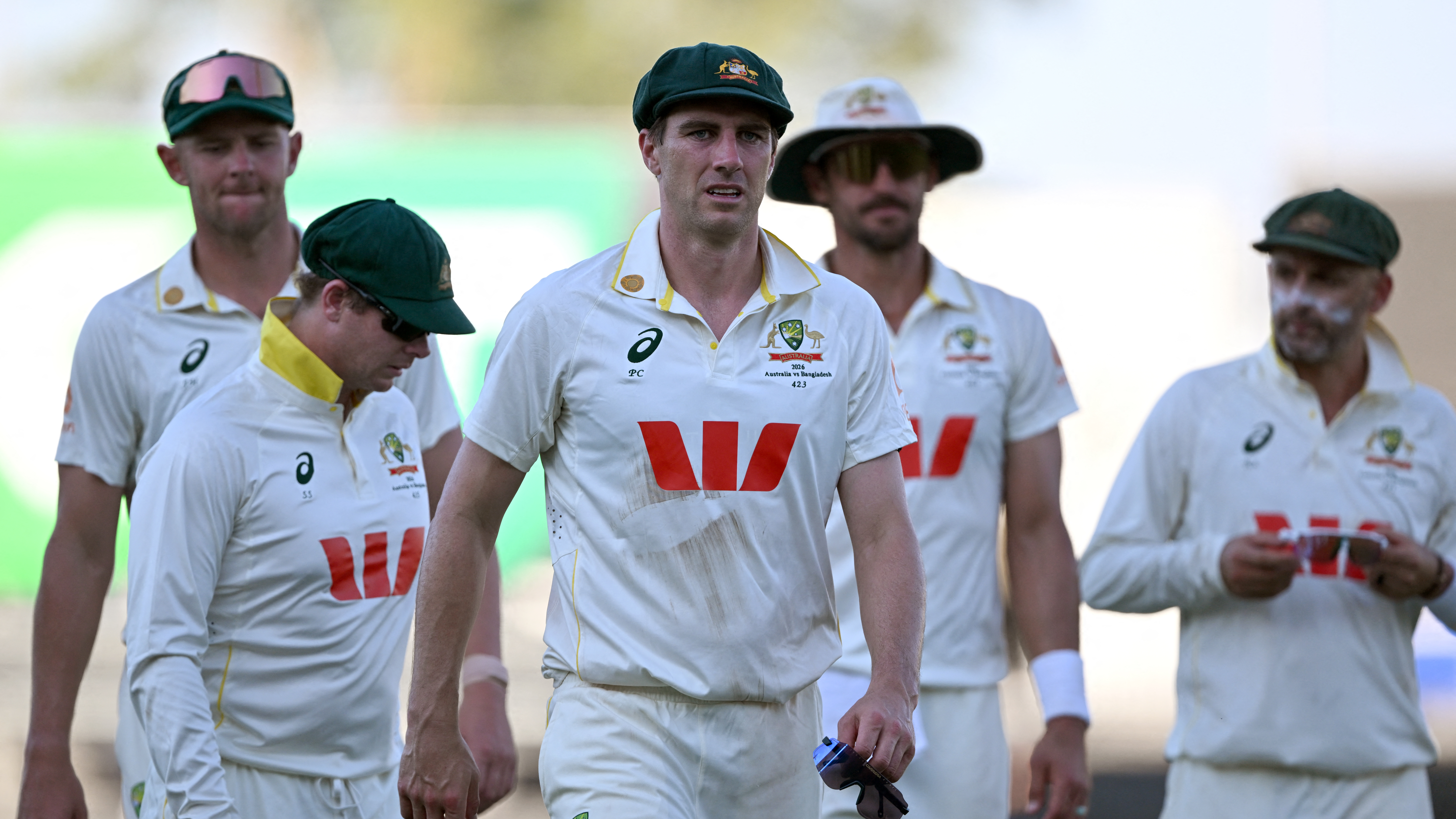 Australia's captain Pat Cummins (C) leads his players off at the end of the second day of the first cricket Test match between Australia and Bangladesh