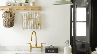 Mono utility room with brass tap, wooden peg rail and laundry essentials