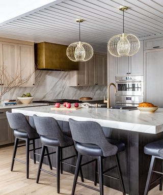 Pale wooden kitchen with marble island and gold range hood