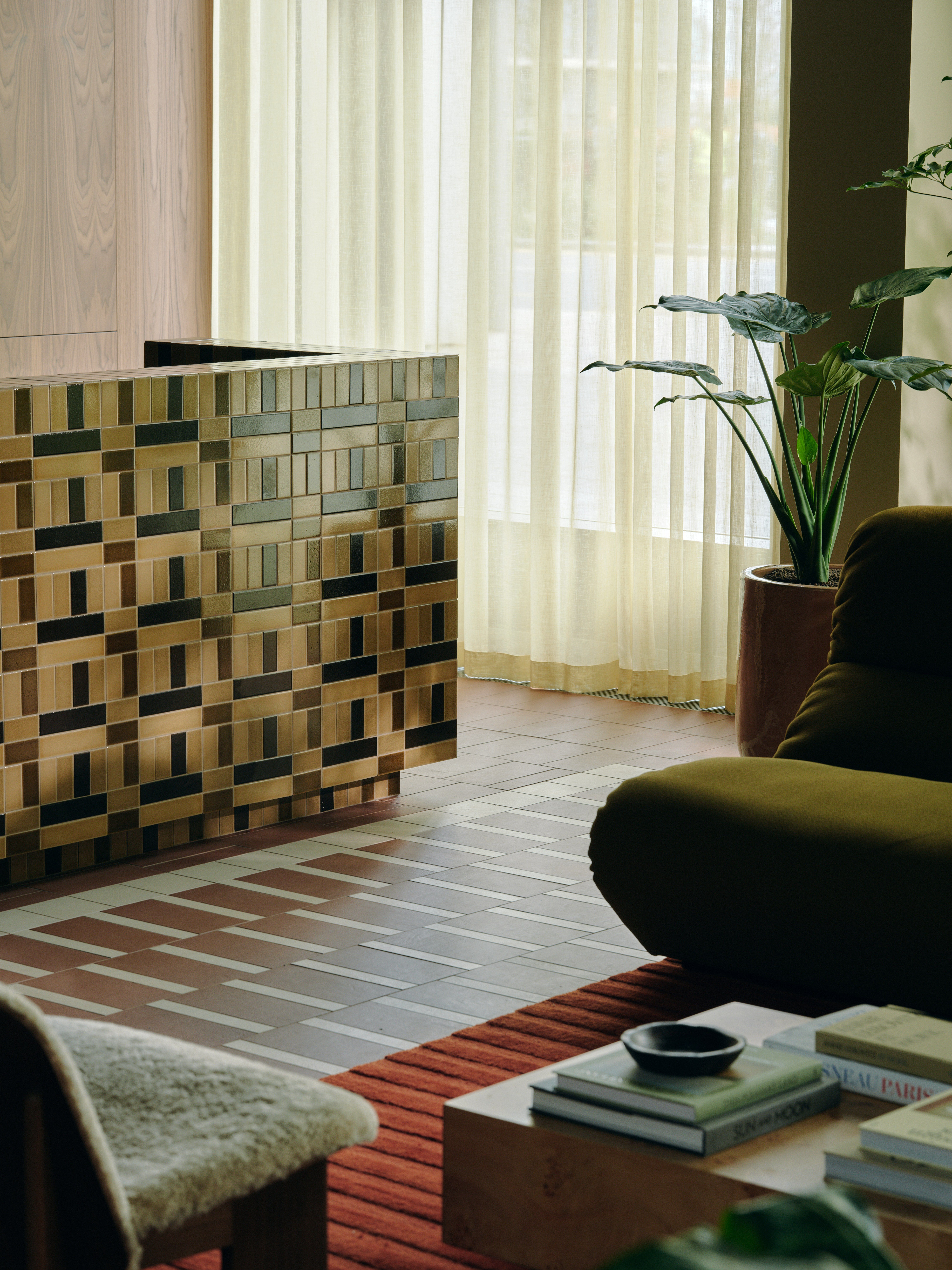 A series of interior shots of a workspace designed with terracotta-hued checkered floors, coffered ceilings in wood and back-lit blocks, pendant, see-through lighting, mid-century furniture, 
