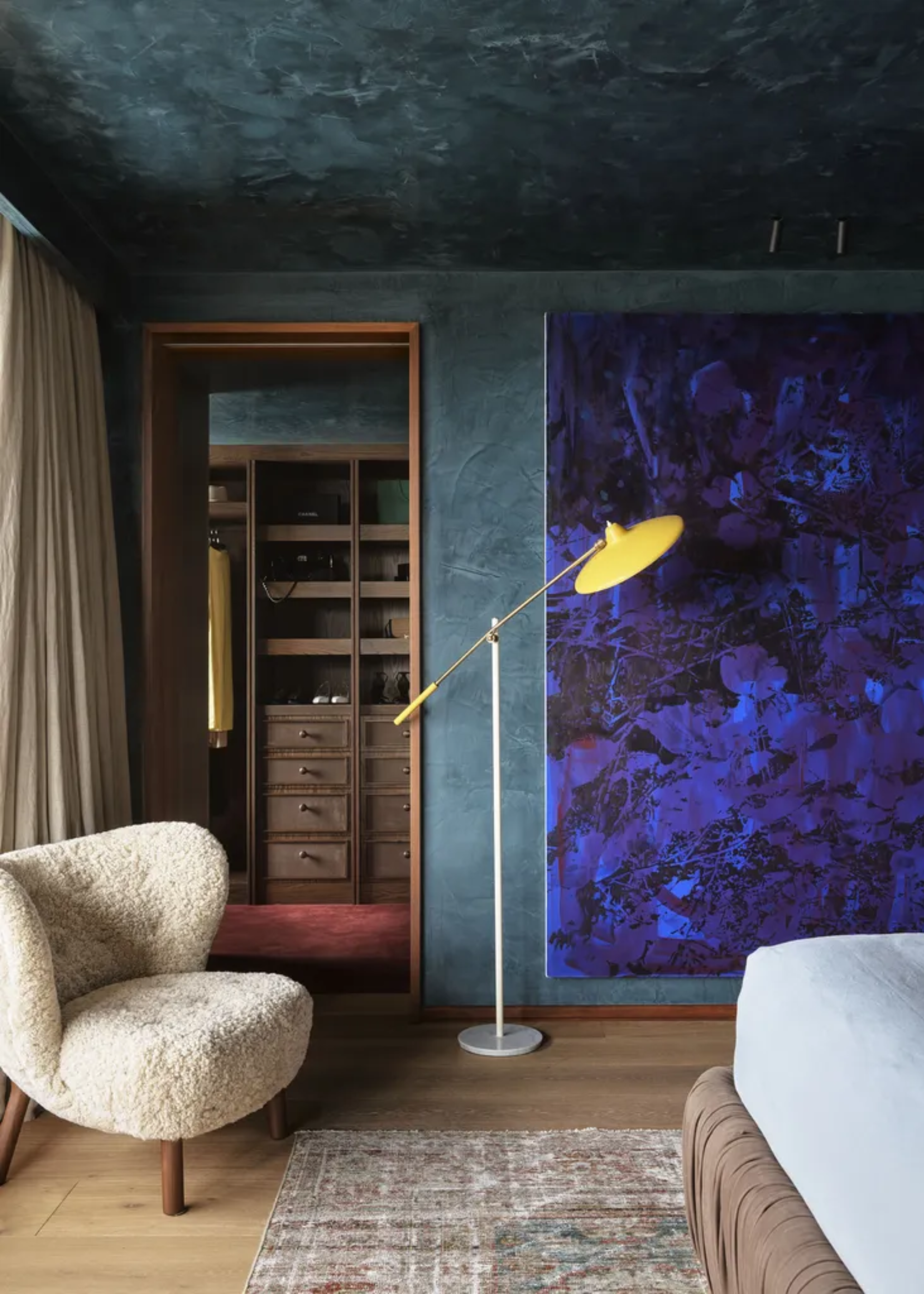 A colorful bedroom with a walk-in wardrobe featuring open shelving and pull-out drawers
