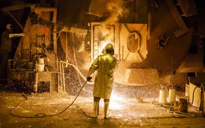 A worker cleans a big melting pot at the Salzgitter AG steelworks in Salzgitter, Germany. 