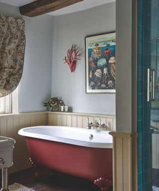 bathroom with red painted bath and light purple walls and sea themed artwork