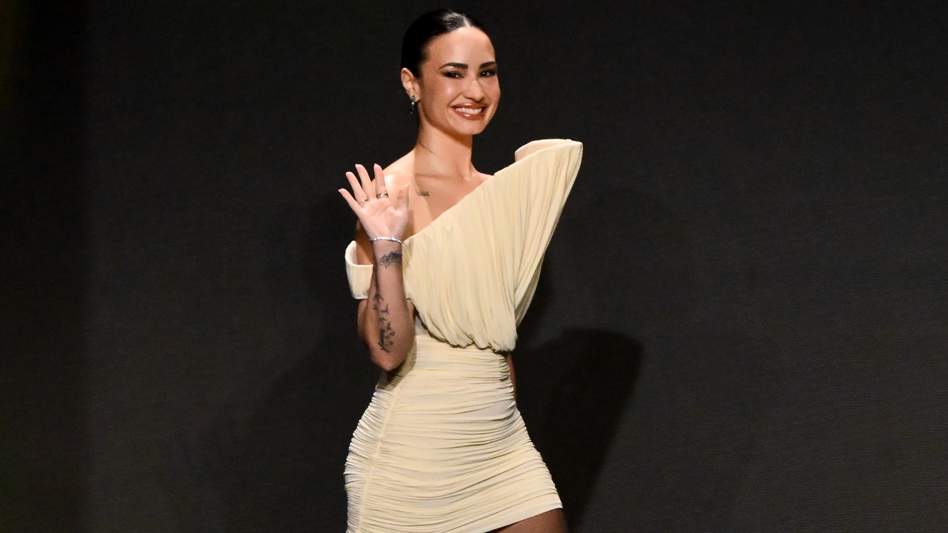 a woman wearing a beige mini dress in front of a black background