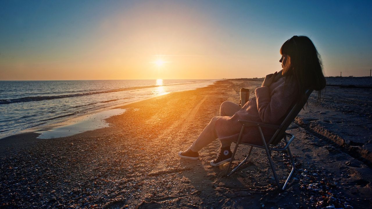 How to relax on Mother&#039;s Day: a woman sits on the beach watching the sunset