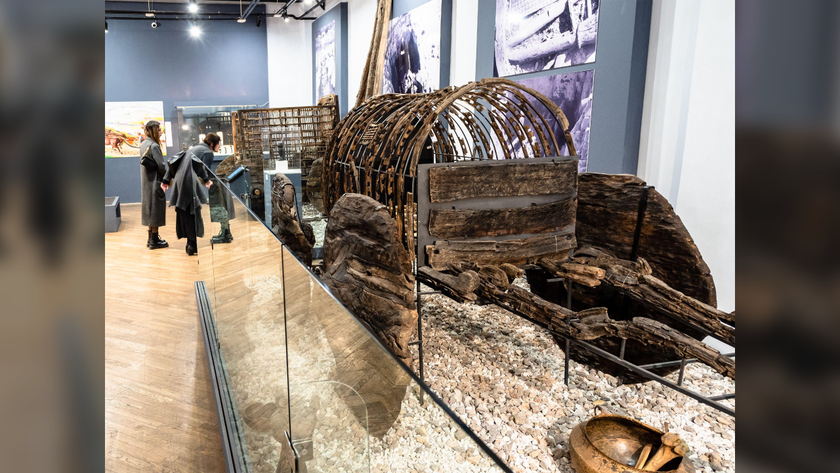 museum exhibit featuring a wooden wagon behind glass