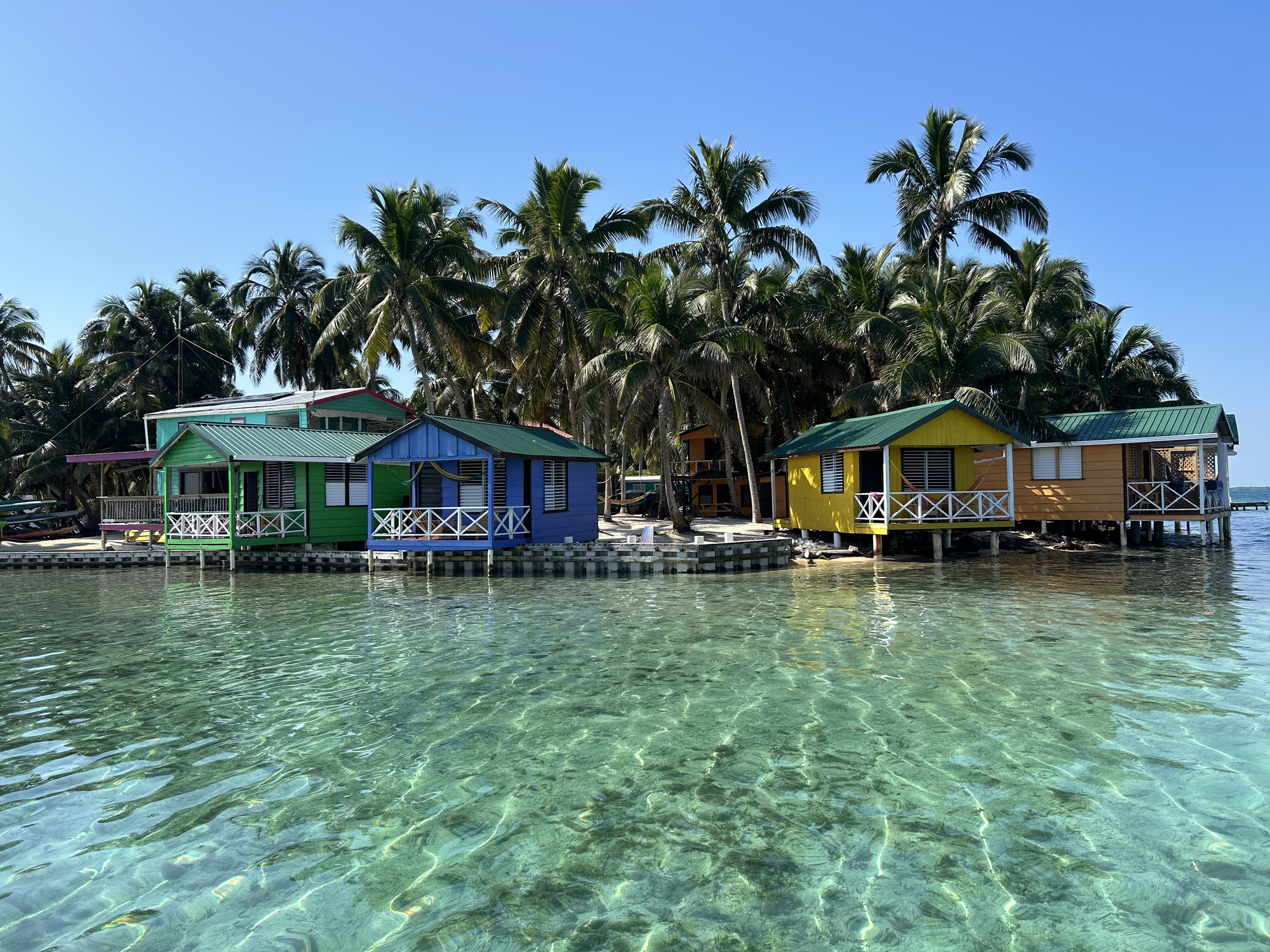 Overwater bungalows and palm trees on Tobacco Caye, Belize, Central America