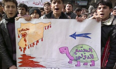 Young Syrian men hold a sign depicting the international community&amp;#039;s turtle-like pace in coming to the aid of a bleeding Syria.