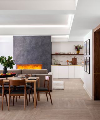 Open plan white kitchen with dining table, green velvet sofa and fireplace