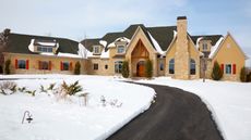 A driveway cleared of snow in front of a large house