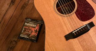 Curt Mangan strings beside a dreadnought acoustic guitar