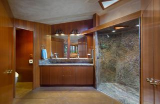 A large bathroom with dark wooden cabinetry and a double vanity with granite sink