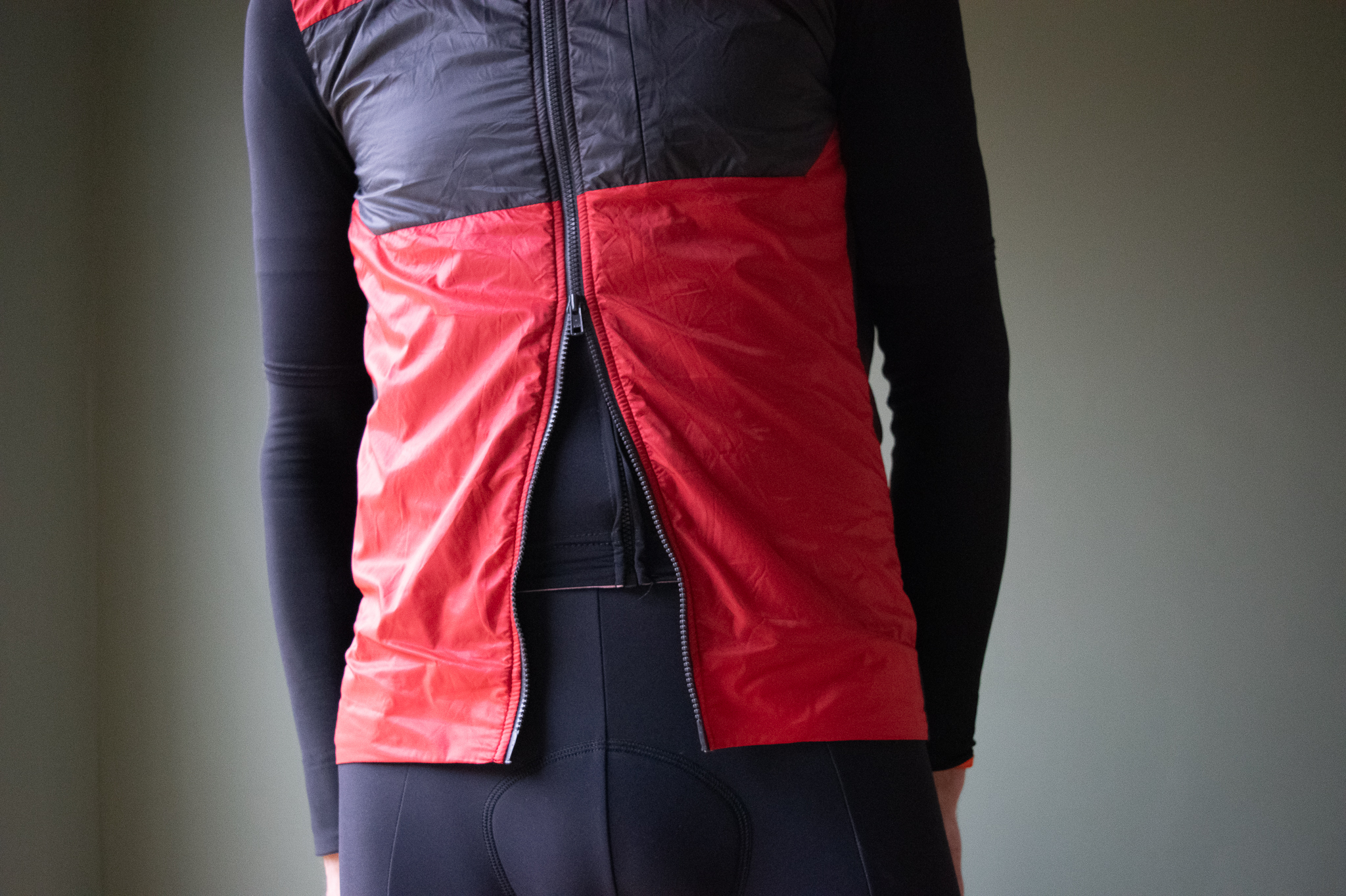 A male cyclist wearing a red Castelli Unlimited Puffy vest