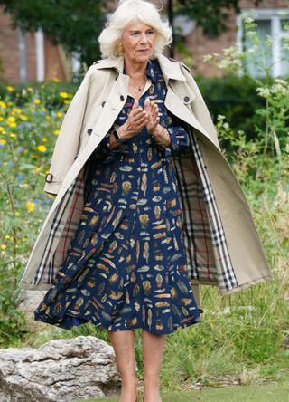 Queen Camilla with a Burberry coat draped over her shoulder