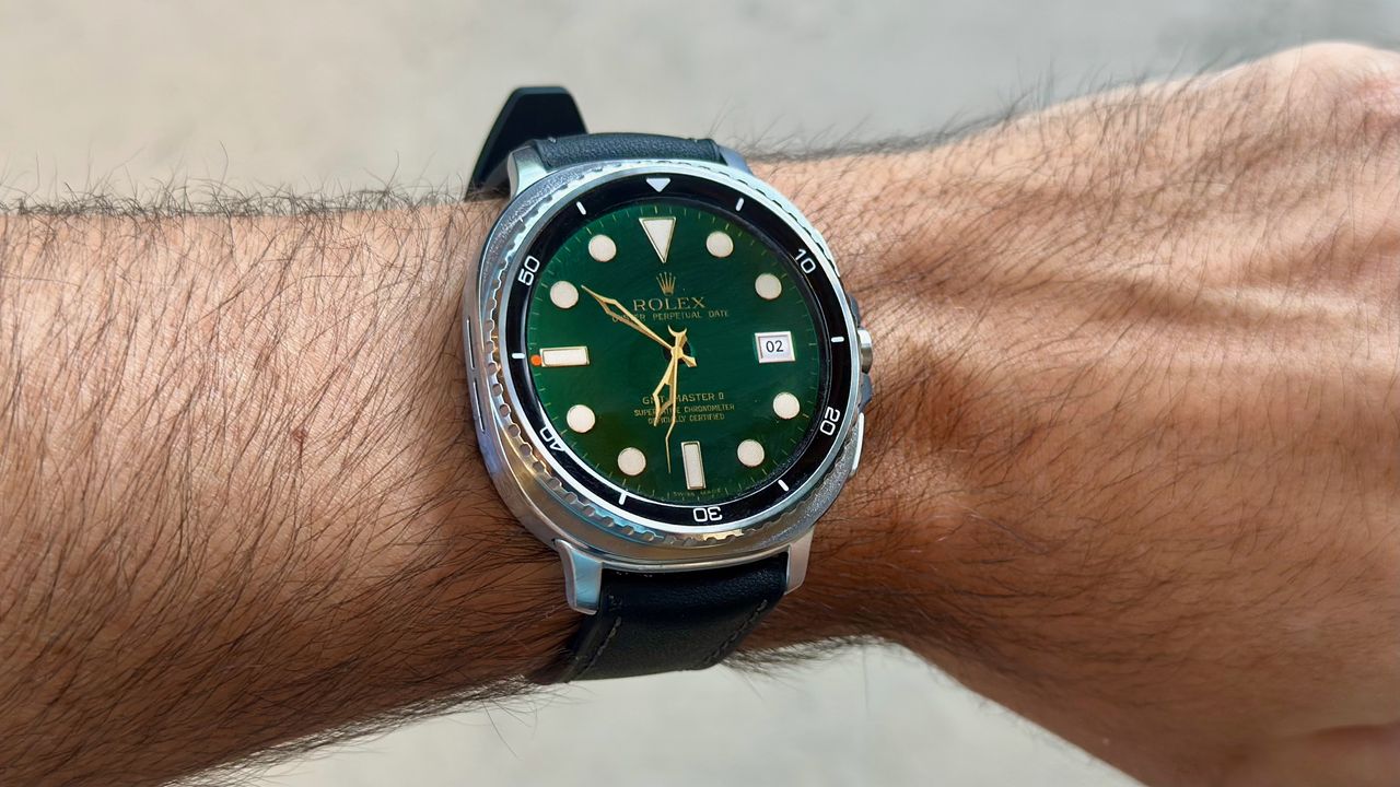 The Samsung Galaxy Watch 8 Classic on a person's wrist, showing a custom watch face from the TIMEFLIK app imitating a Rolex luxury watch face.
