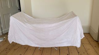 Dunelm Heated Airer With Wings with a bedsheet over it