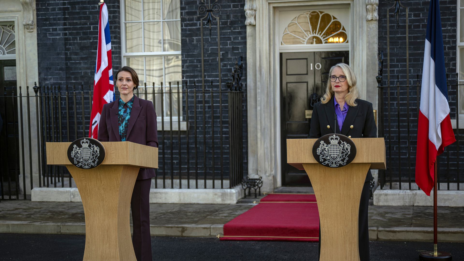 an image of suranne jones and julie deplu in character as the PM and French President standing by lecturns giving a speech outside 10 downing st
