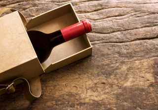 An open box with a bottle of wine showing.