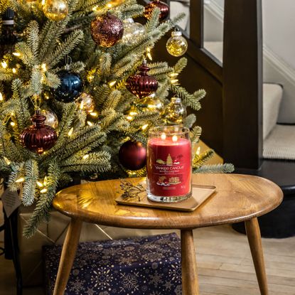 Yankee Candle Big Apple Christmas candle on table in front of Christmas tree